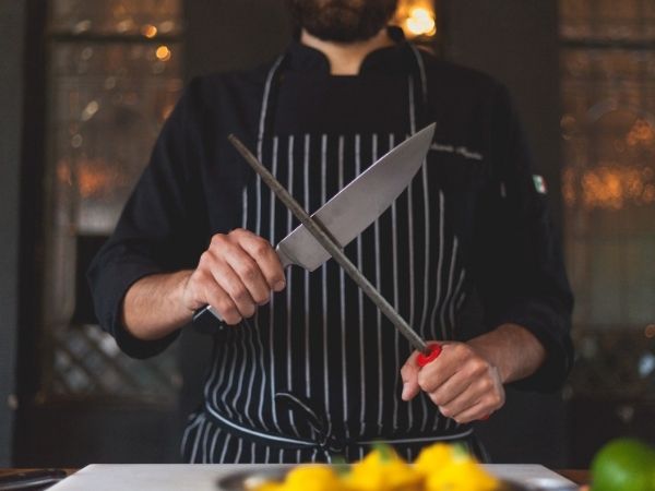 Close-up of a chef sharpening a kitchen knife with a honing steel
