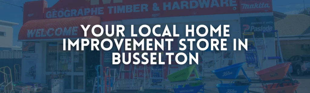 Front storefront exterior of Geographe Timber & Hardware in Busselton, displaying product signs, wheelbarrows, and ladders under a blue overlay with text reading Your Local Home Improvement Store in Busselton.
