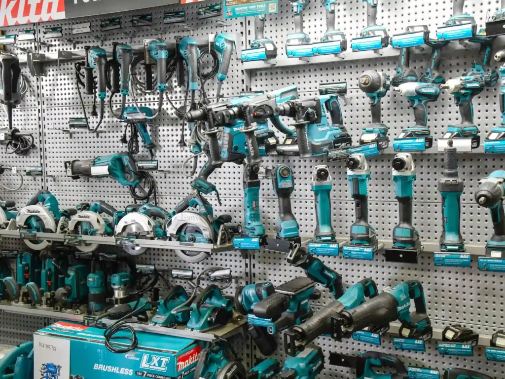 A comprehensive retail display wall filled with teal Makita power tools, including cordless drills, impact drivers, circular saws, angle grinders, and reciprocal saws on hooks.